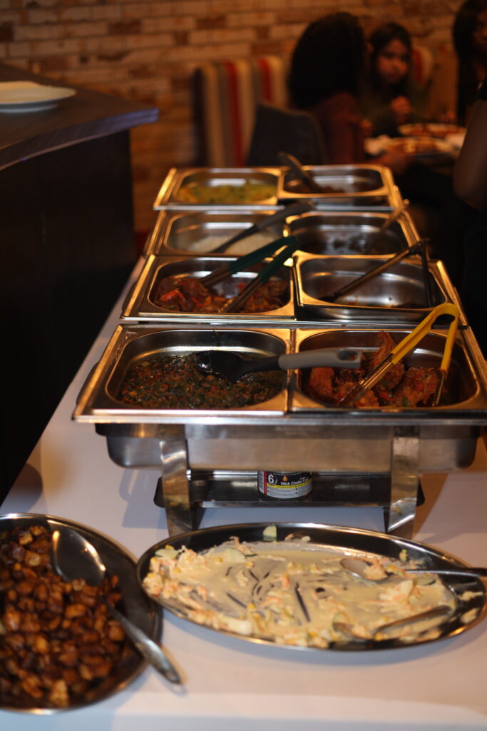 A buffet table with assorted meats, chicken, plantain and coselaw at demi's nigerian restaurant 